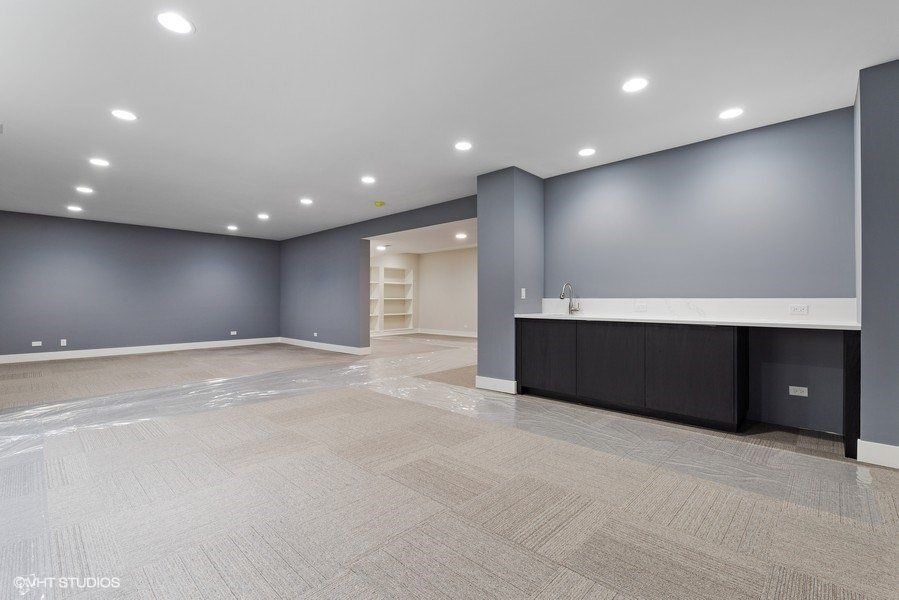 An empty basement with blue walls and a sink.