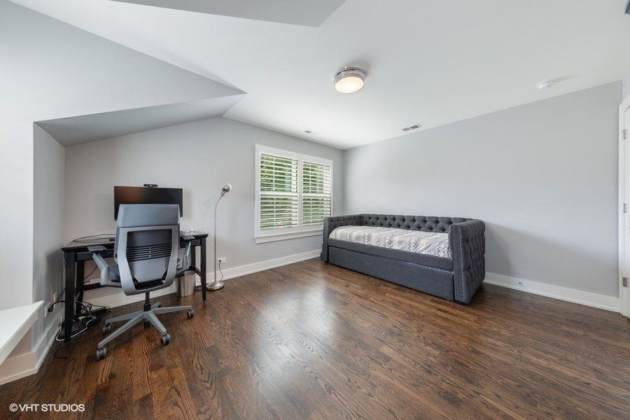 A bedroom with a couch , desk and chair.