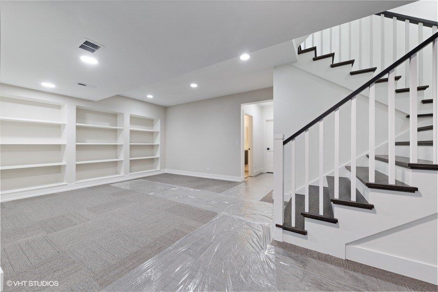 An empty basement with a staircase and shelves.