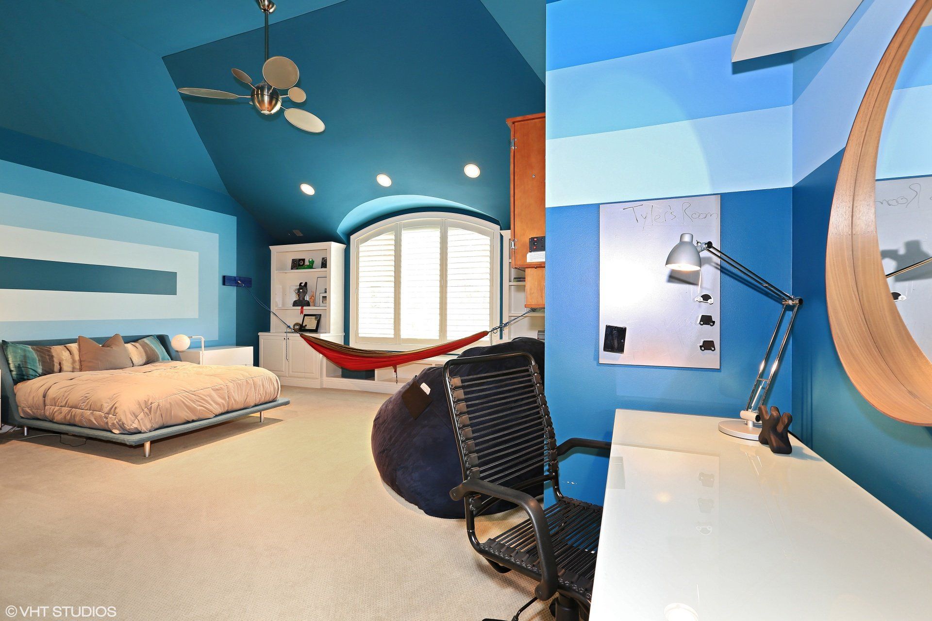 A bedroom with blue walls and a hammock in the corner