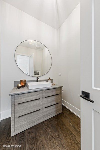 A bathroom with a sink and a round mirror