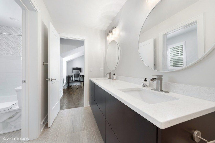 A bathroom with two sinks and a round mirror.