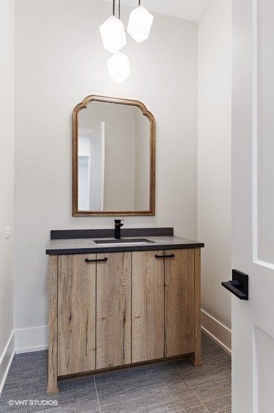 A bathroom with a wooden vanity , mirror and sink.