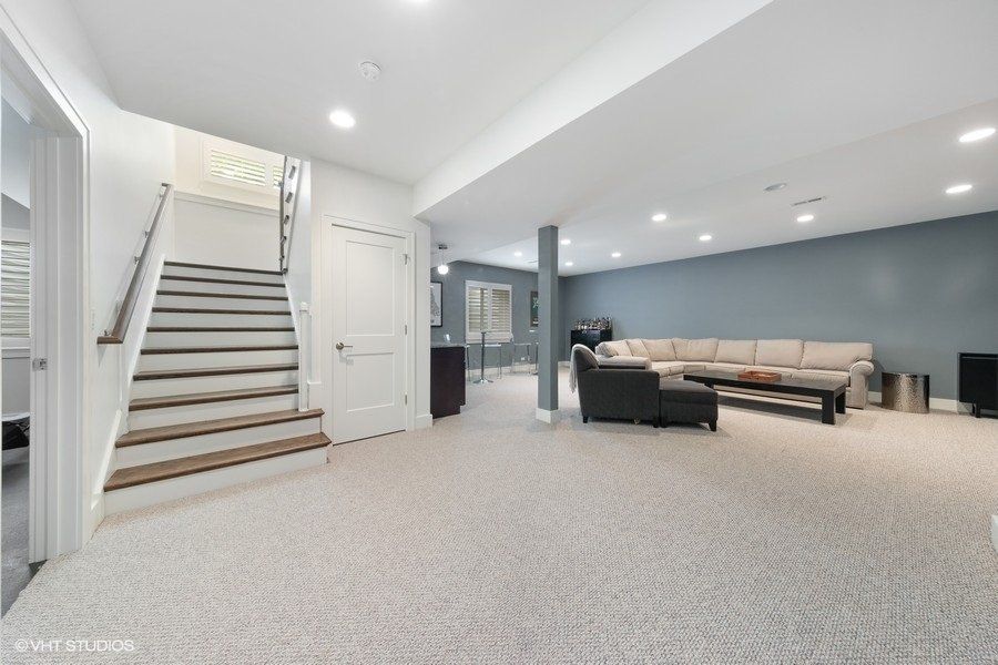 A living room with a couch and stairs in a basement.