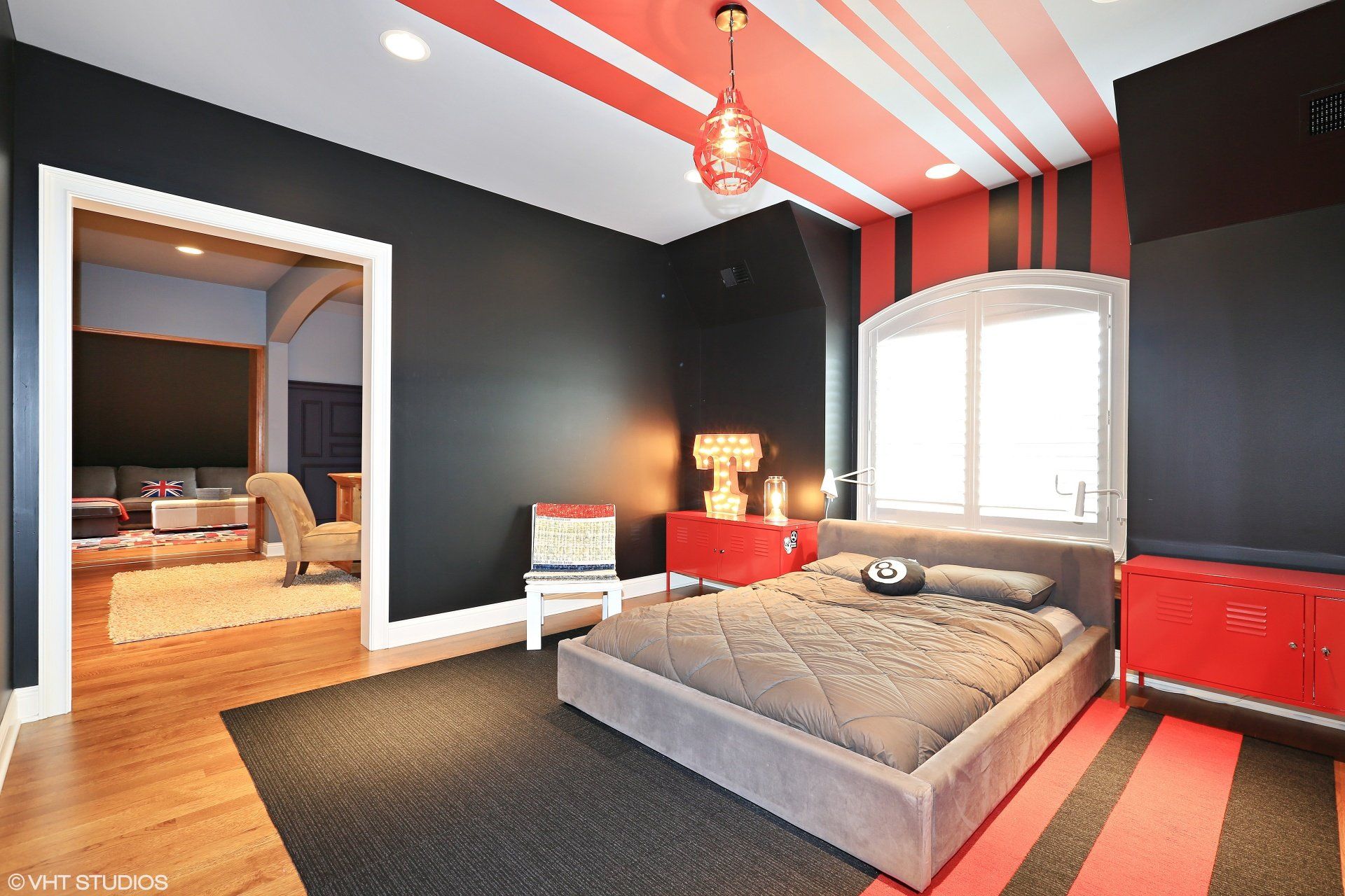 A bedroom with black walls and red stripes on the ceiling