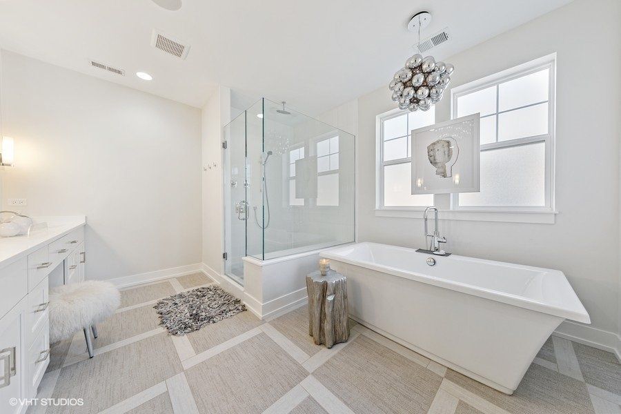 A bathroom with a tub , shower , sink and window.