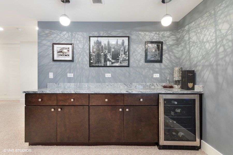 A kitchen with wooden cabinets , granite counter tops and a wine cooler.