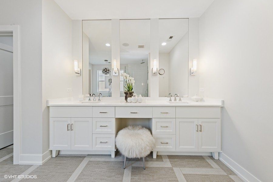 A bathroom with two sinks , two mirrors and a stool.