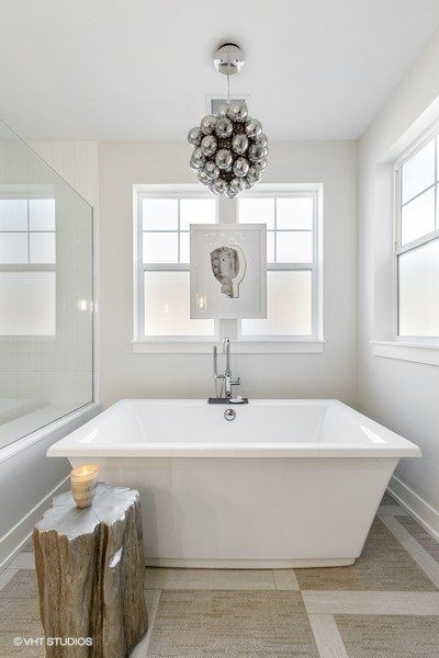A white bathtub in a bathroom next to a window