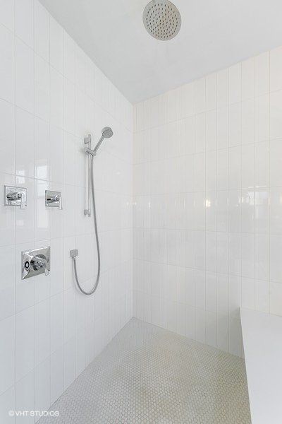A bathroom with white tiles and a shower head