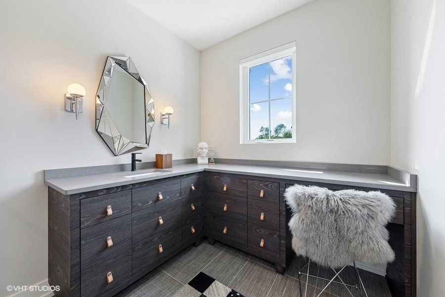 A bathroom with a vanity , mirror , dresser and chair.