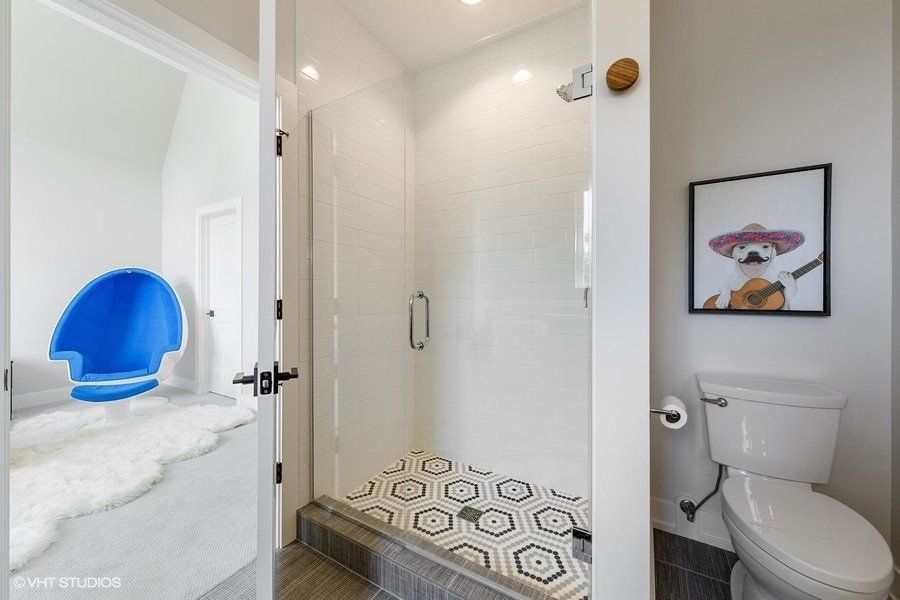 A bathroom with a toilet , shower , and picture on the wall.