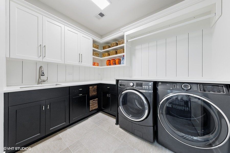 A laundry room with black cabinets , a washer and dryer , and a sink.