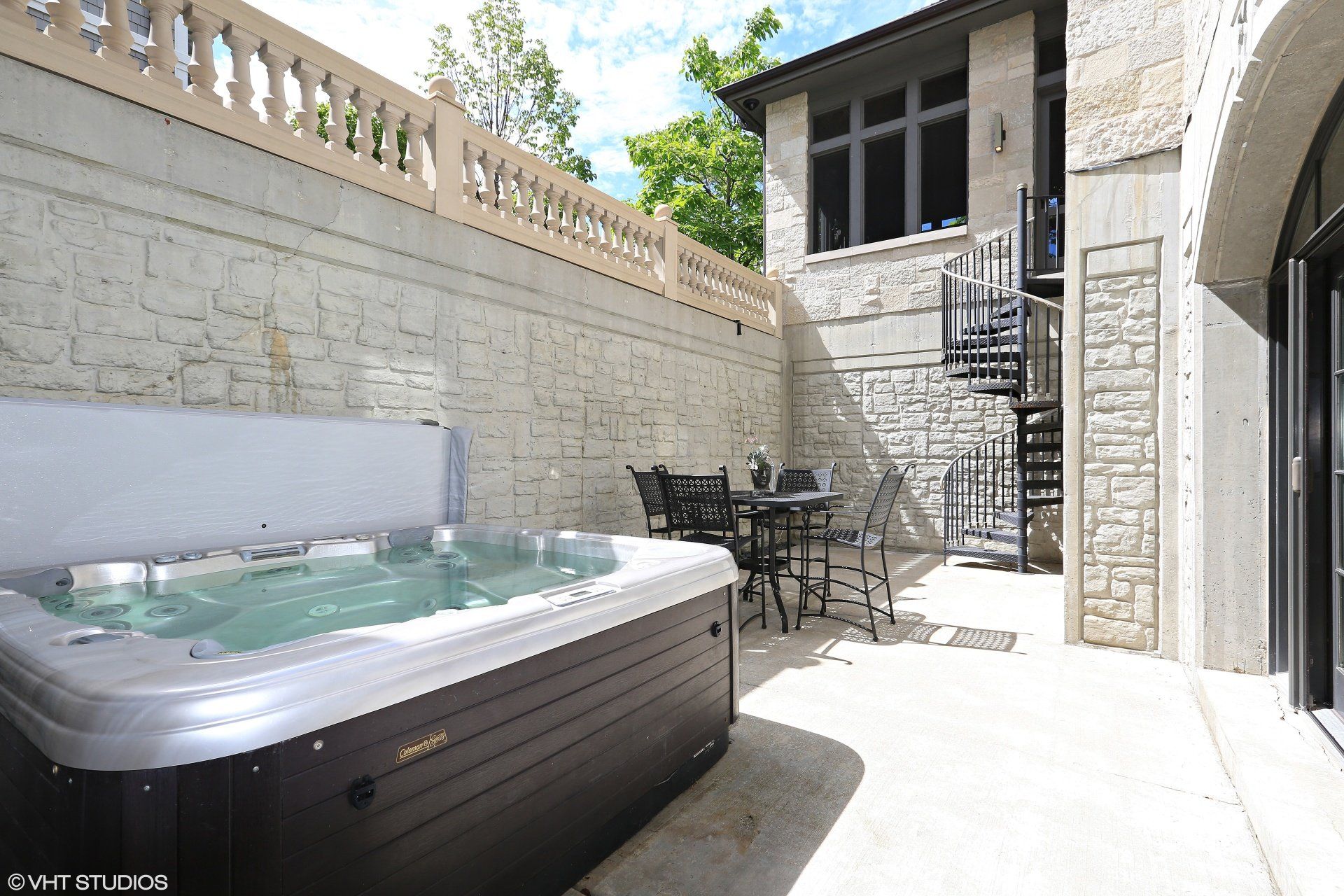 A hot tub is sitting on a patio next to a house.