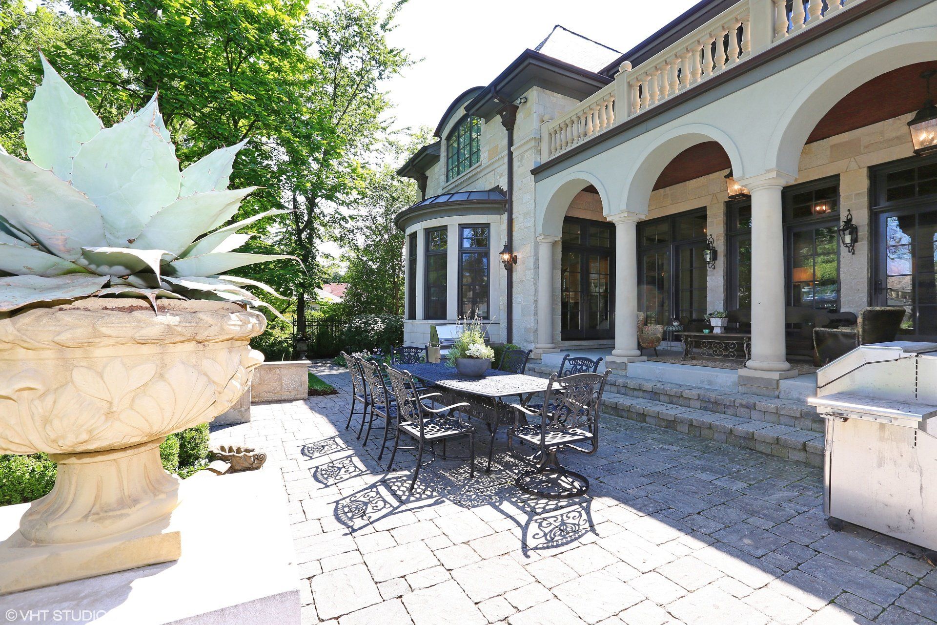 A patio with a table and chairs in front of a large house
