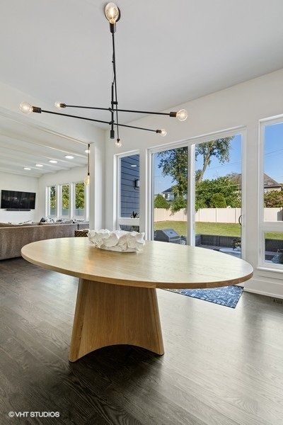 A round wooden table in a living room with a chandelier hanging from the ceiling.