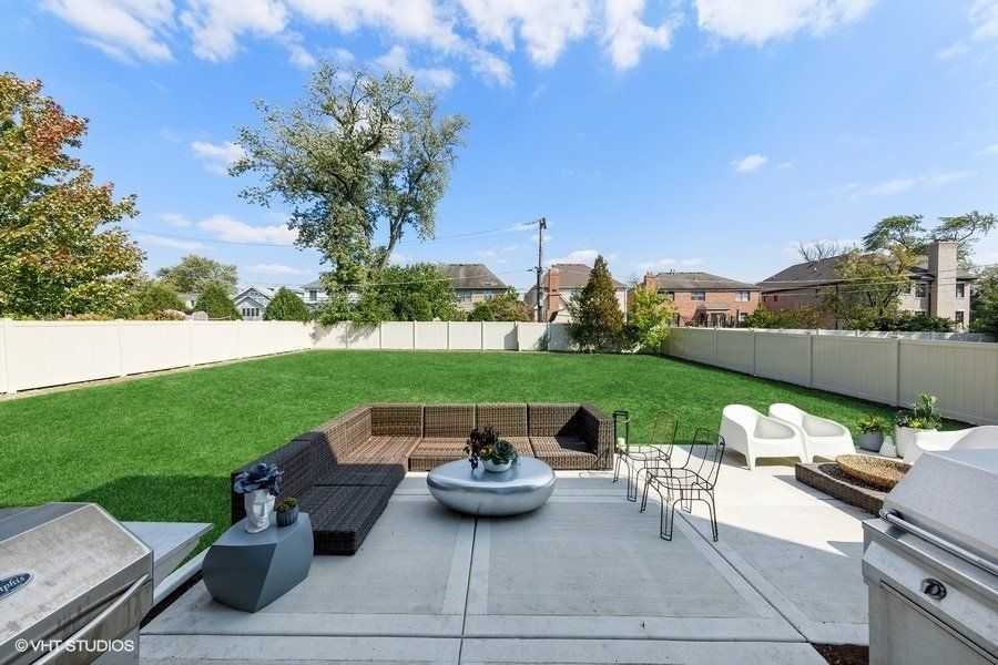 A patio with a couch , table , chairs and a grill.