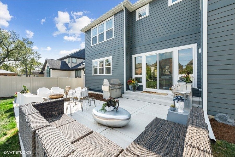 The backyard of a house with a patio area and a grill.