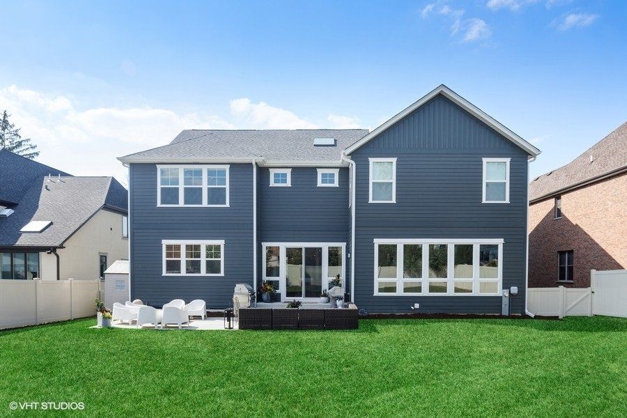 The back of a house with a lot of windows and a large lawn.