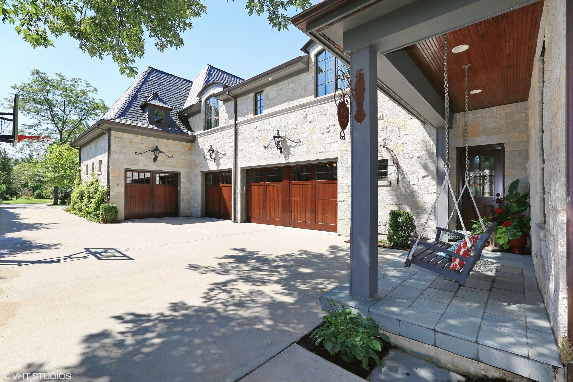 A large house with a porch swing and a basketball hoop