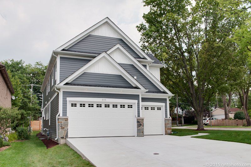 A large house with two garage doors and a driveway.