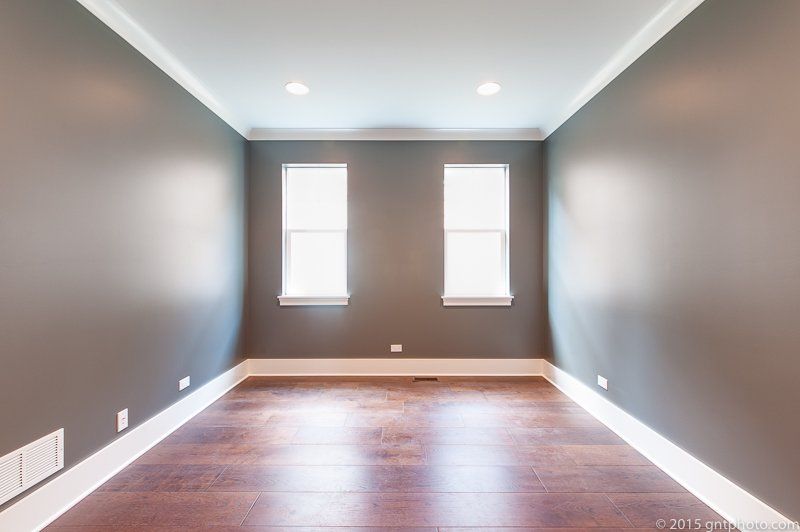 An empty room with two windows and gray walls