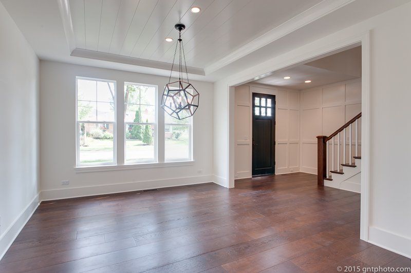 An empty living room with hardwood floors and a chandelier.
