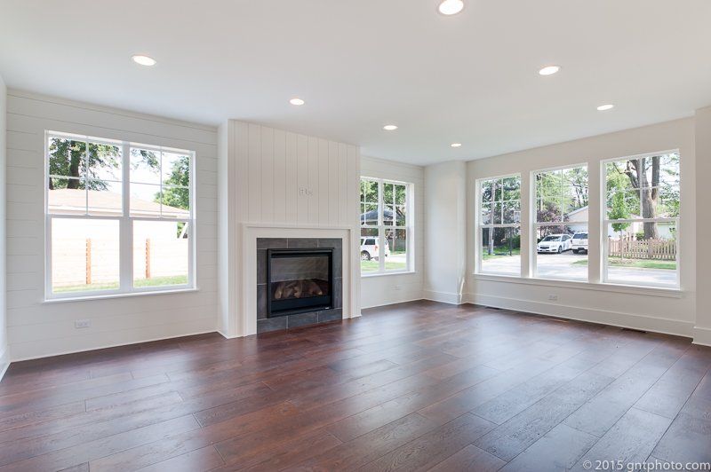 An empty living room with hardwood floors and a fireplace.