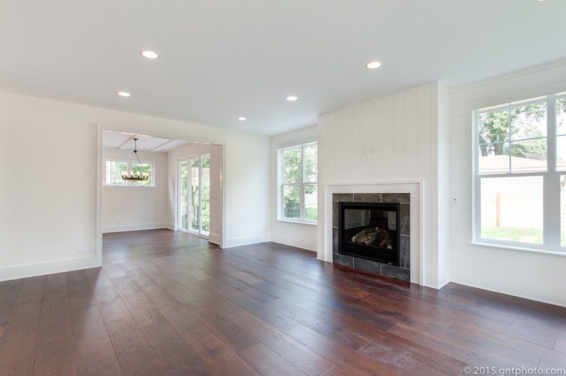 An empty living room with hardwood floors and a fireplace.