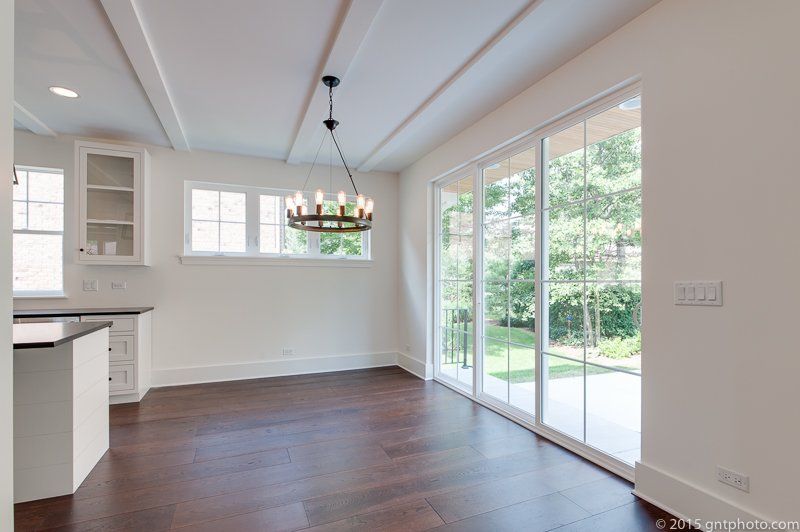 An empty room with sliding glass doors and a chandelier hanging from the ceiling.