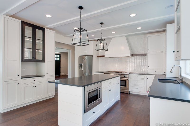 A kitchen with white cabinets and black counter tops