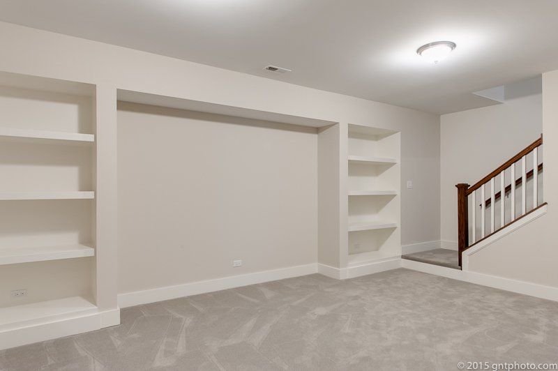 An empty room with shelves and stairs in a house.