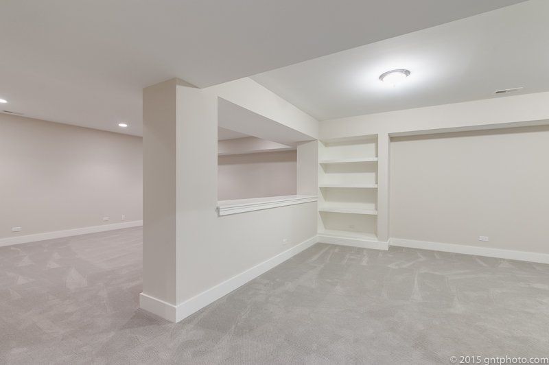 An empty room with white walls and a gray carpet.