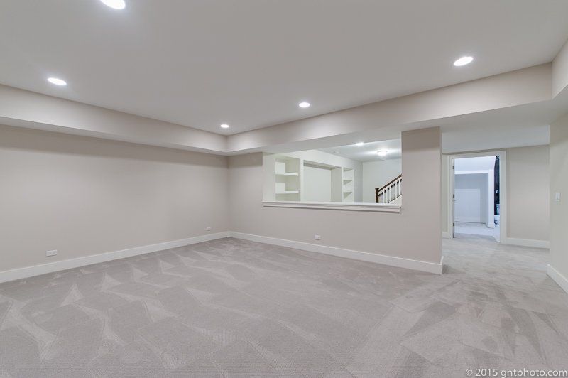 An empty basement with a carpeted floor and white walls.