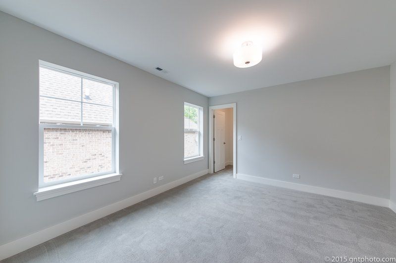 An empty bedroom with two windows and a ceiling light.