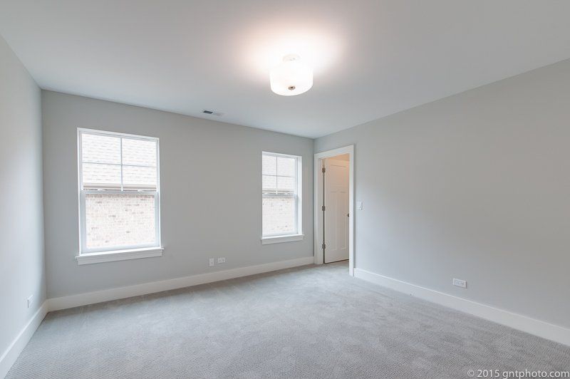 An empty bedroom with two windows and a ceiling light