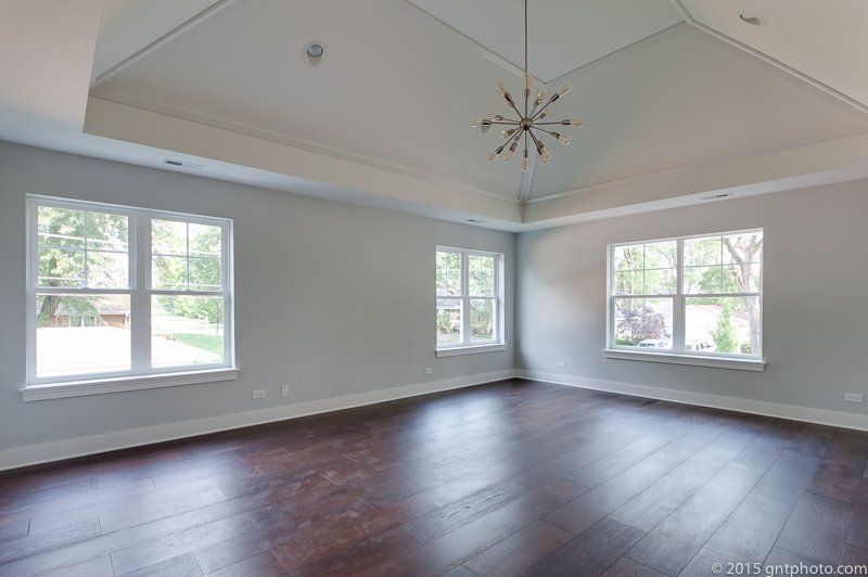 A large empty room with hardwood floors and a vaulted ceiling.