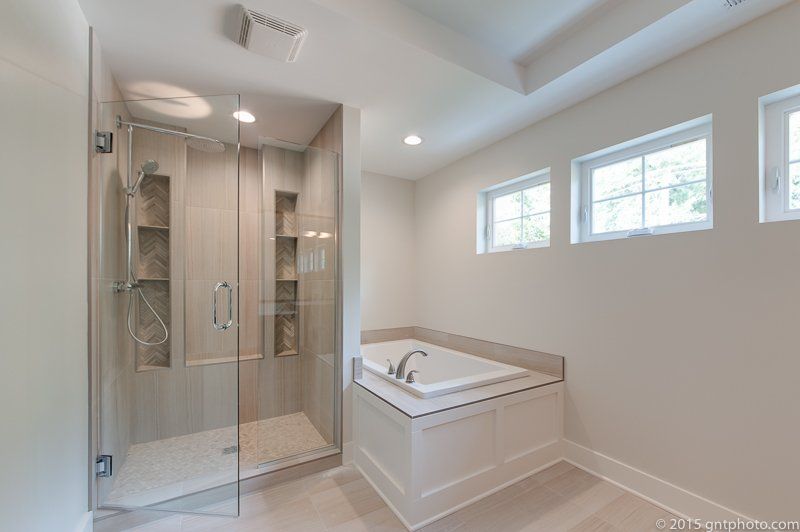 A bathroom with a tub , shower , and window.