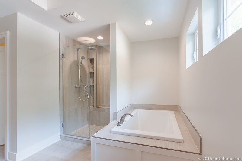 A bathroom with a tub , shower , and window.