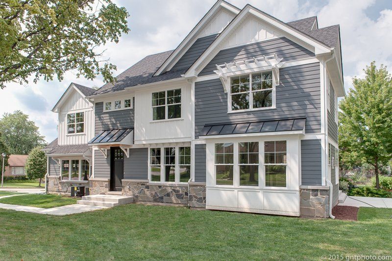A large house with a lot of windows is sitting on top of a lush green lawn.