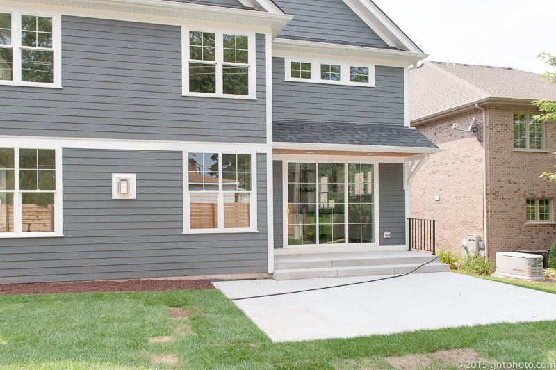 The back of a gray house with a brick house in the background.