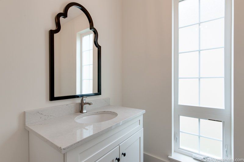 A bathroom with a sink , mirror and window.