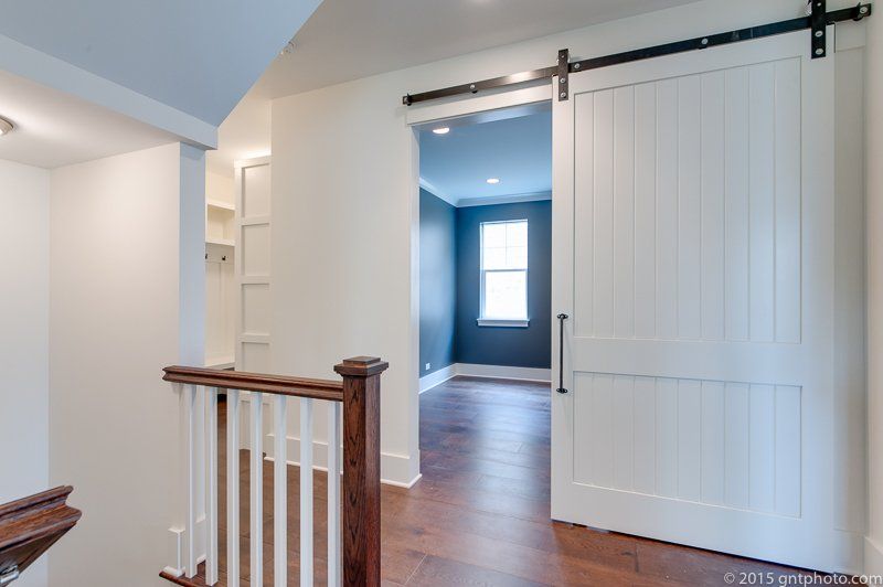 A staircase with a sliding barn door leading to a room.