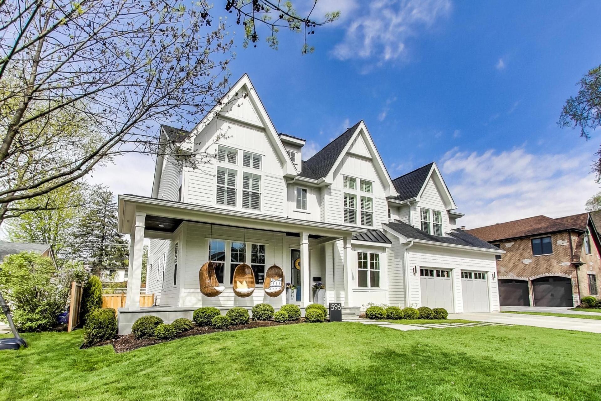 A large white house with a black roof is sitting on top of a lush green lawn.