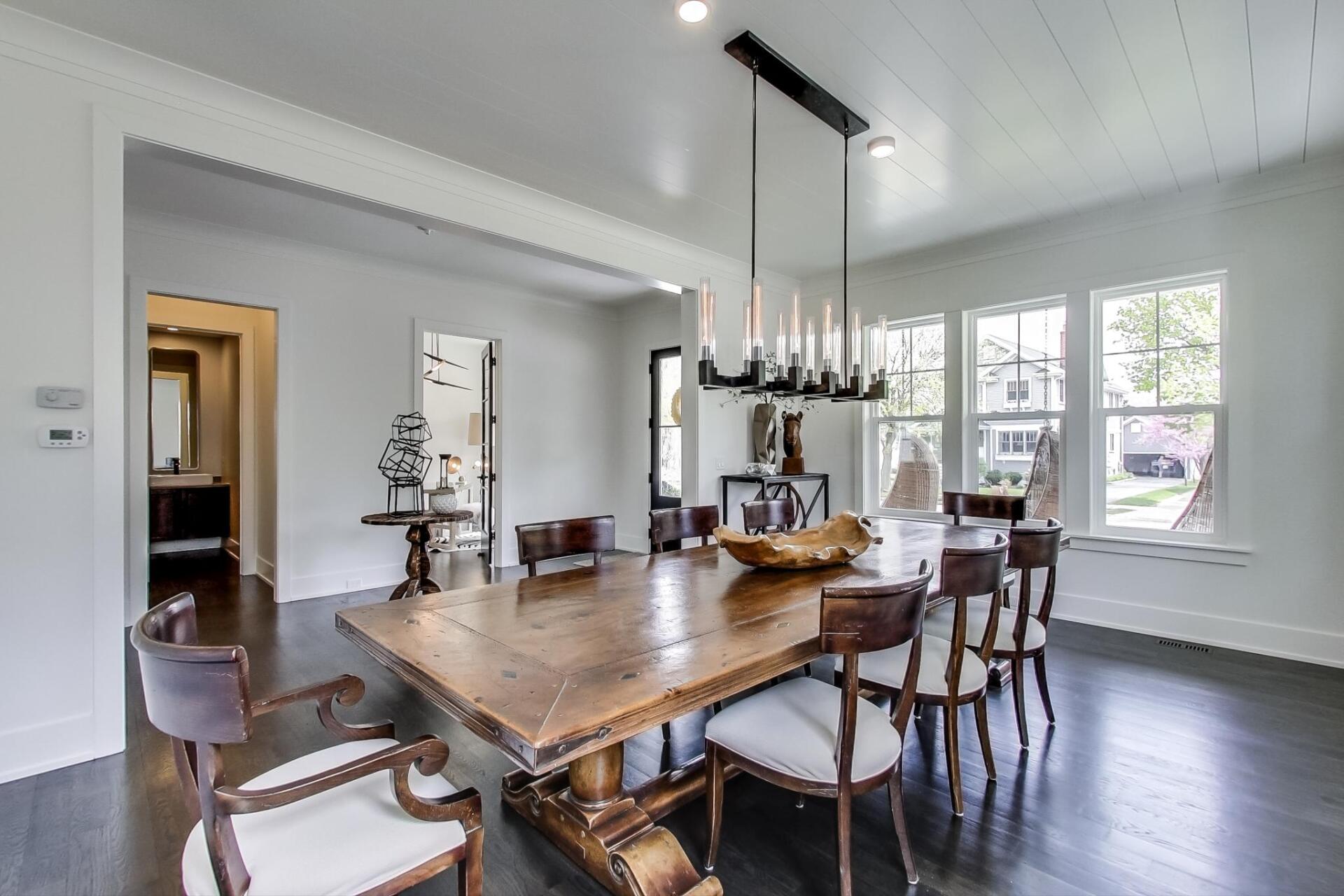 A dining room with a large wooden table and chairs.