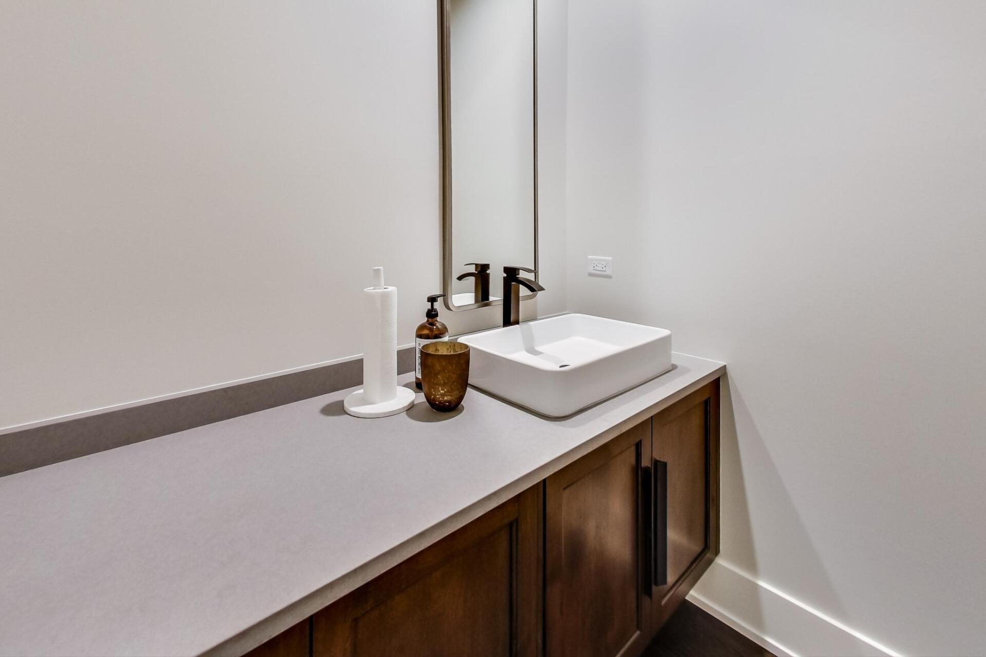 A bathroom with a sink , mirror and cabinets.