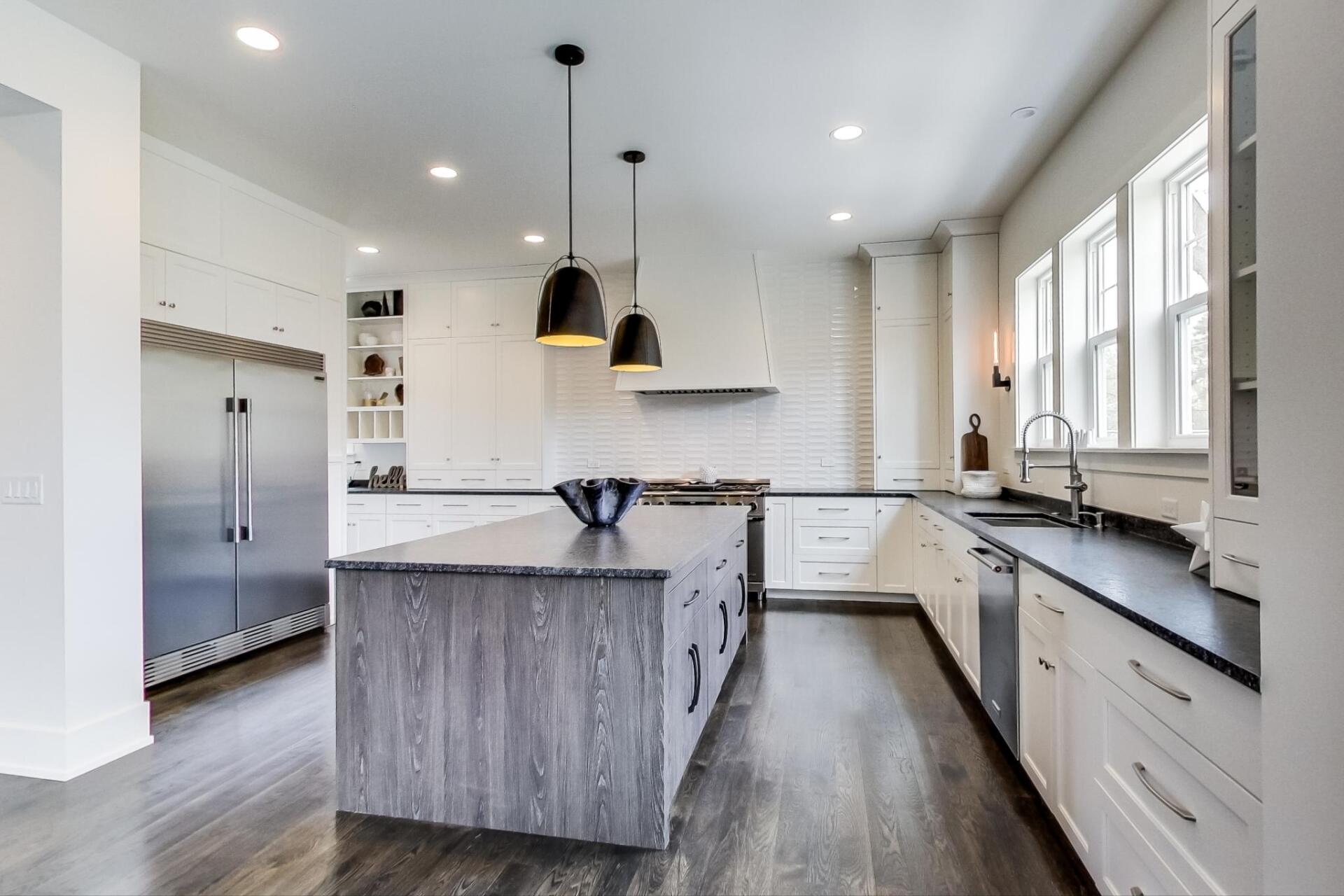 A kitchen with a large island in the middle and stainless steel appliances.