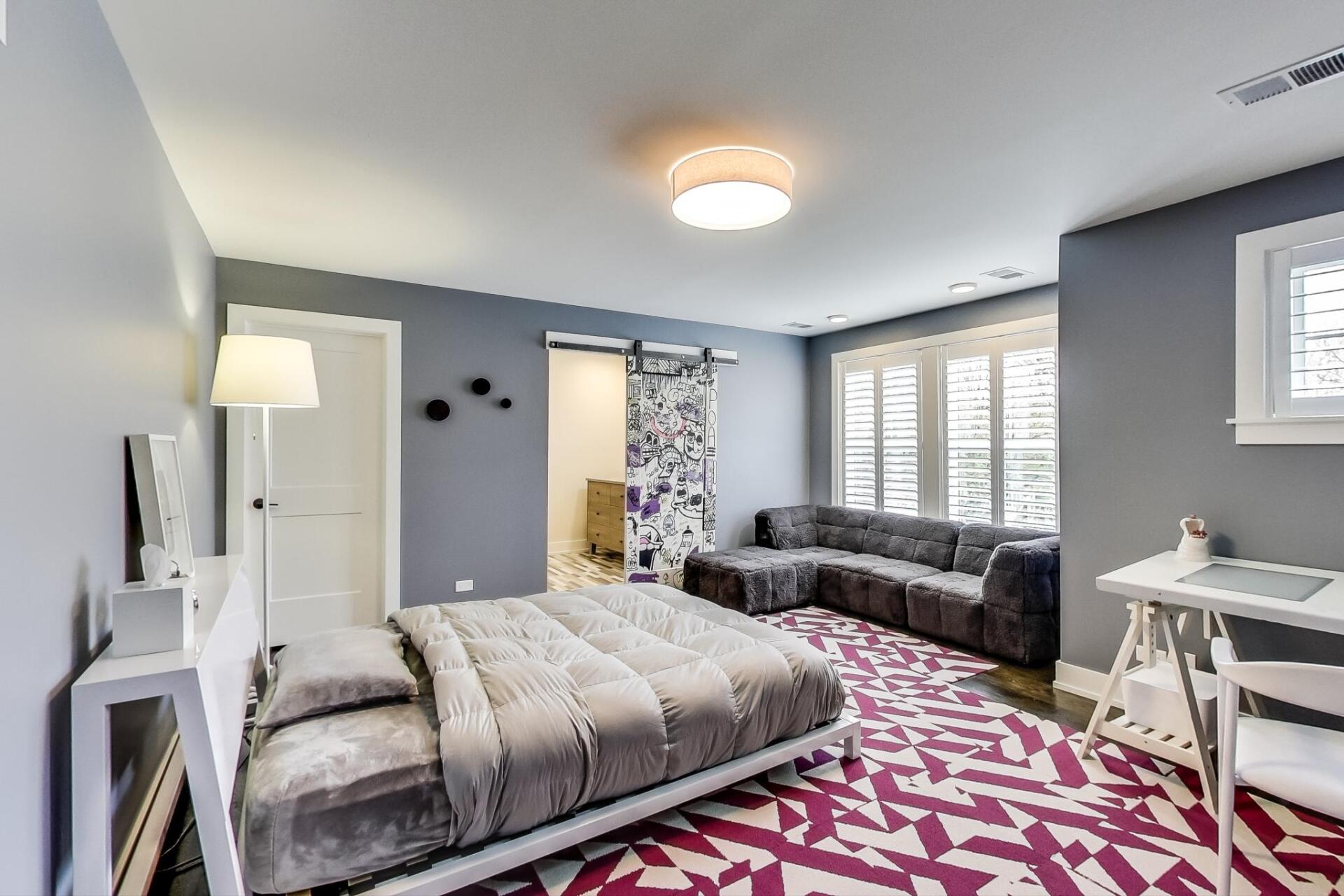 A bedroom with a bed , couch , desk and rug.