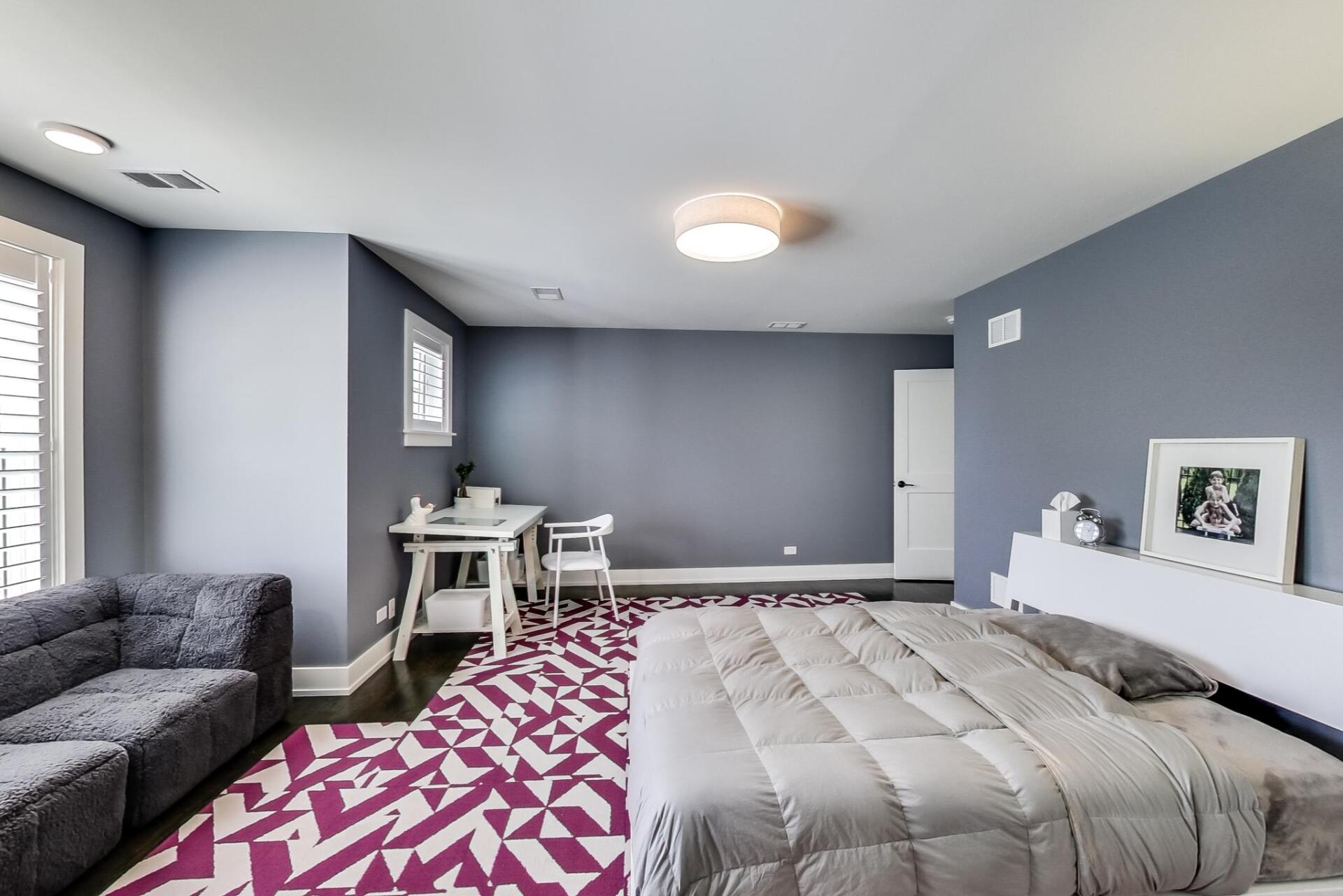 A bedroom with a large bed and a purple rug