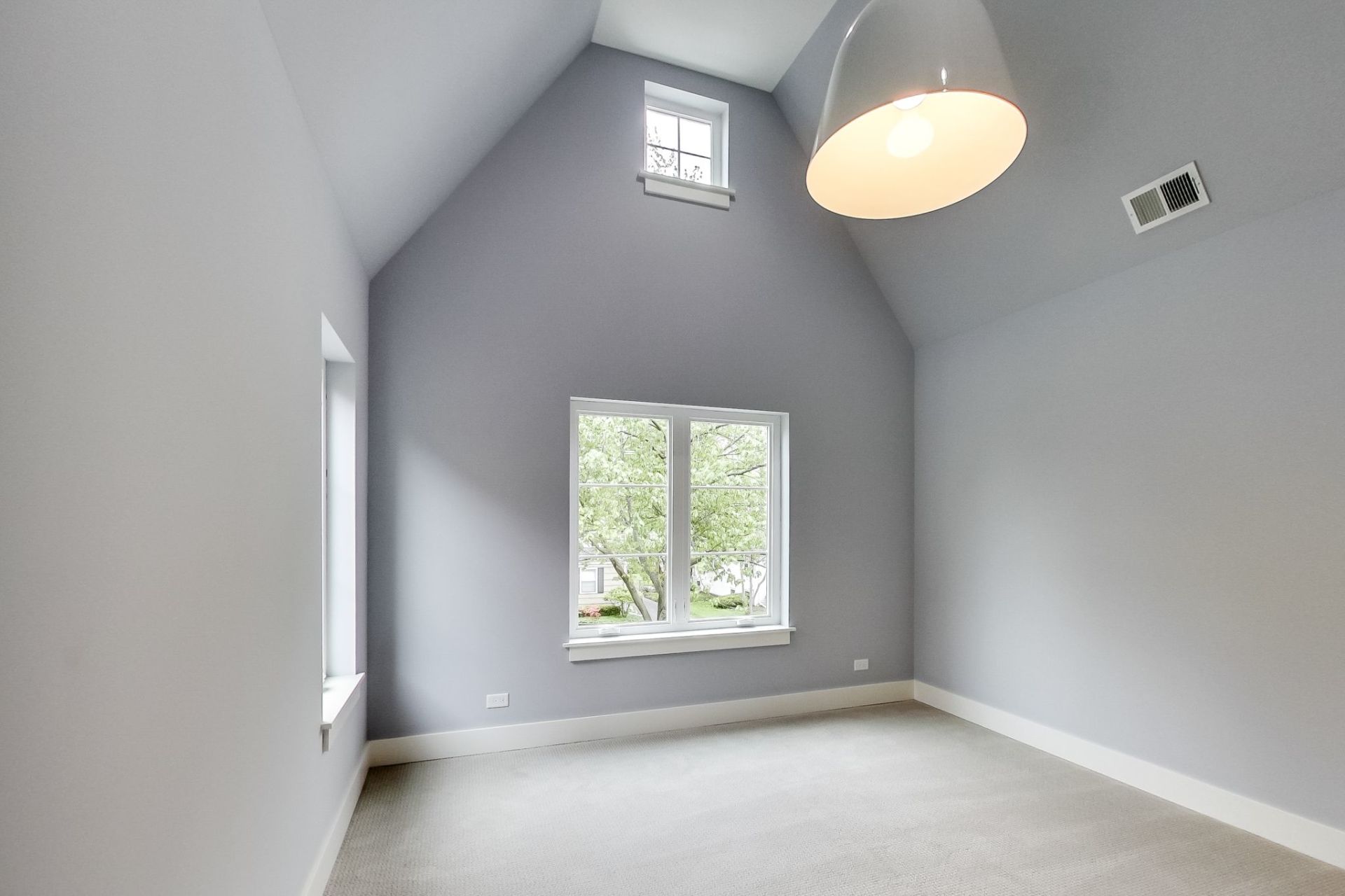 An empty room with a vaulted ceiling and two windows.